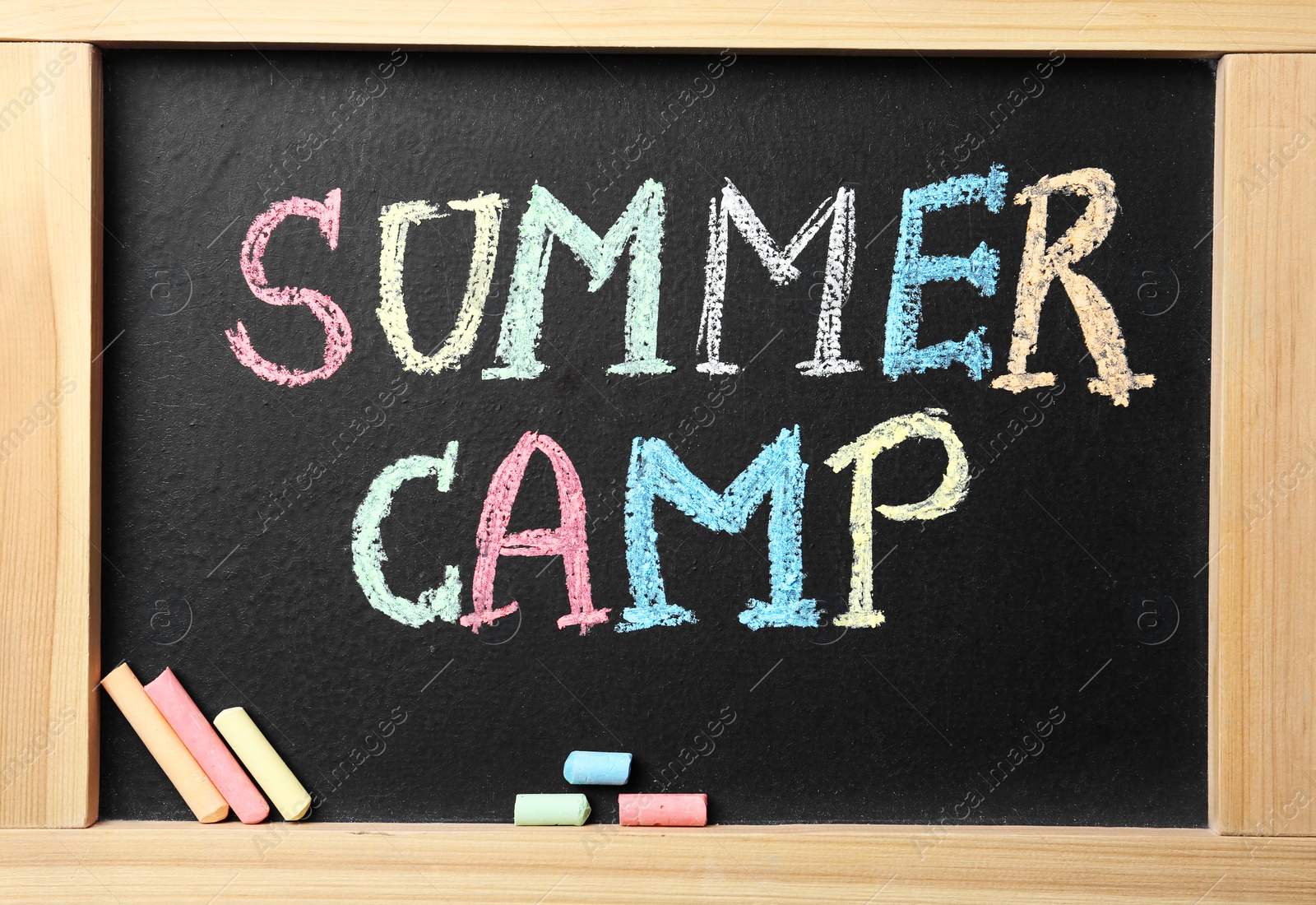 Photo of Small blackboard with text SUMMER CAMP and chalk sticks, flat lay