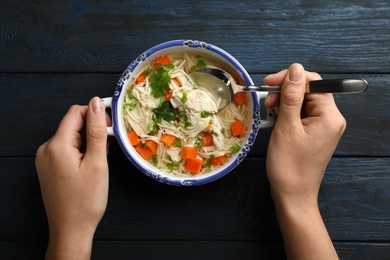 Photo of Woman eating fresh homemade chicken soup at table, top view