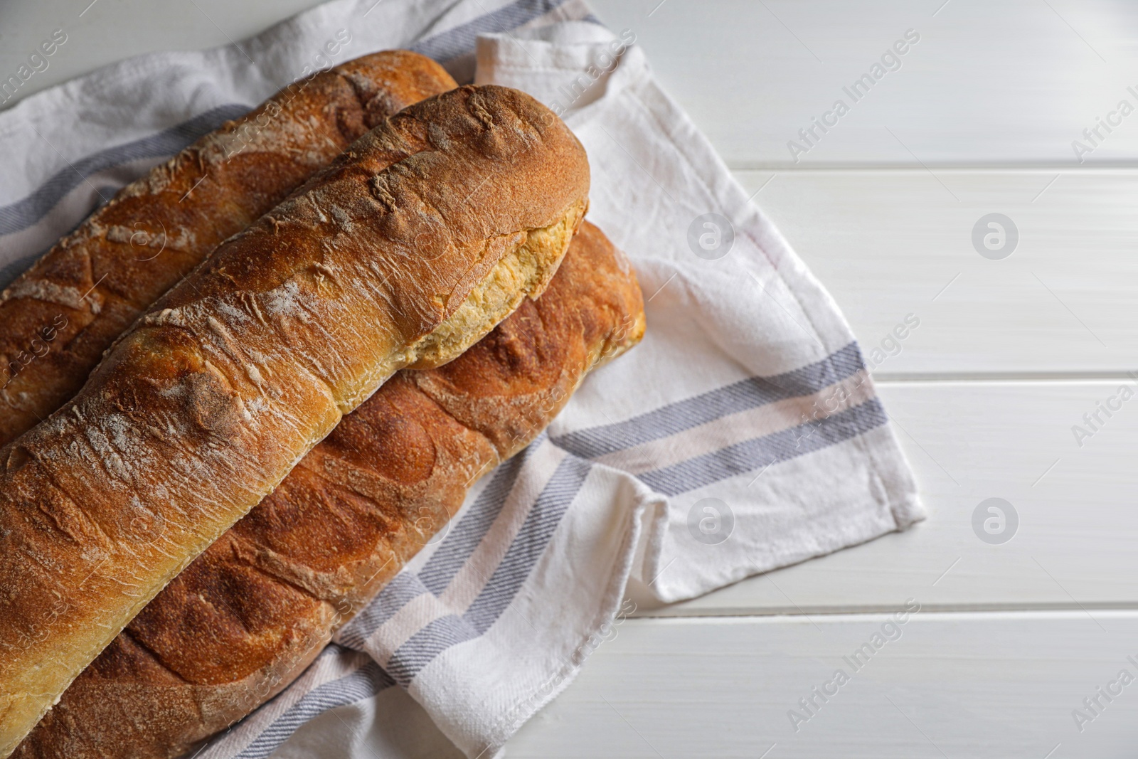 Photo of Fresh crispy ciabattas on white wooden table, top view. Space for text