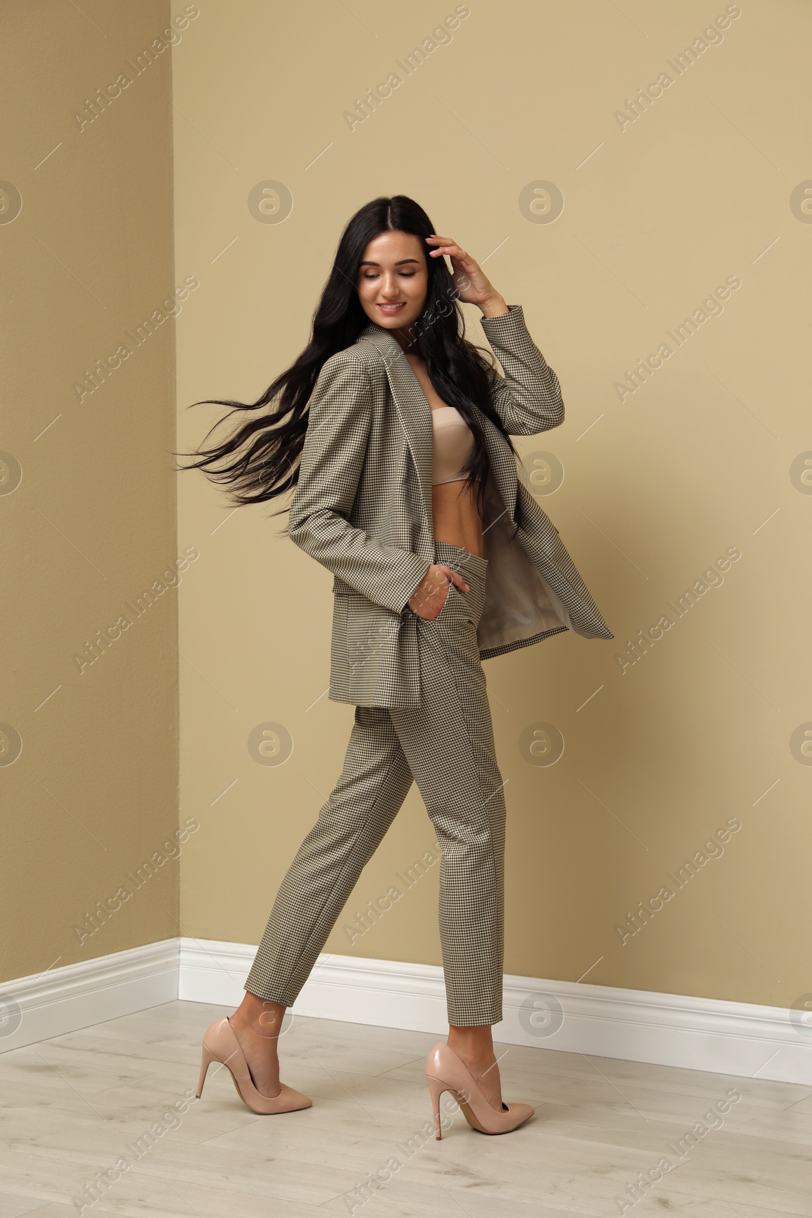 Photo of Full length portrait of beautiful woman in formal suit near beige wall