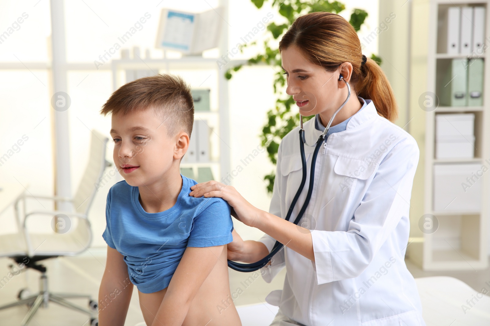 Photo of Children's doctor examining patient with stethoscope in hospital