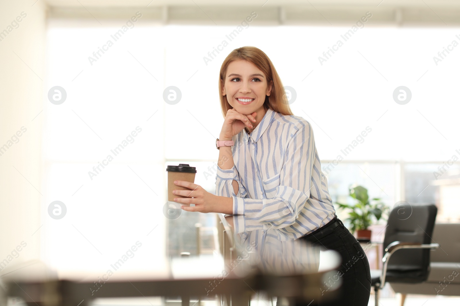 Photo of Young businesswoman with cup of coffee relaxing in office during break