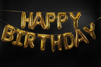 Phrase HAPPY BIRTHDAY made of golden balloon letters on dark background