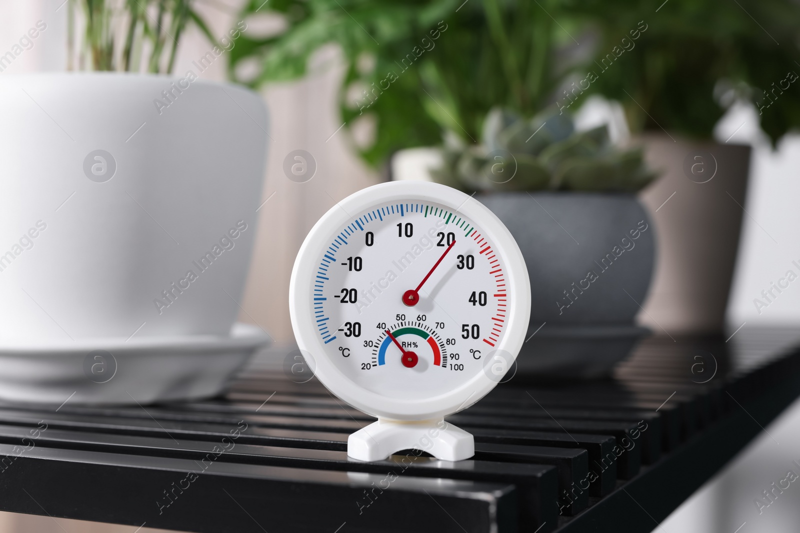 Photo of Round mechanical hygrometer on black table indoors
