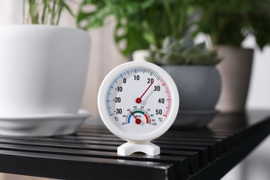 Photo of Round mechanical hygrometer on black table indoors