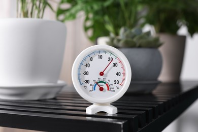 Round mechanical hygrometer on black table indoors