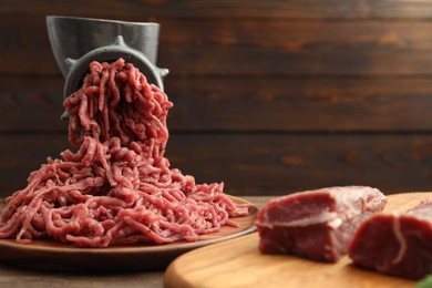 Photo of Manual meat grinder with beef on wooden table, space for text