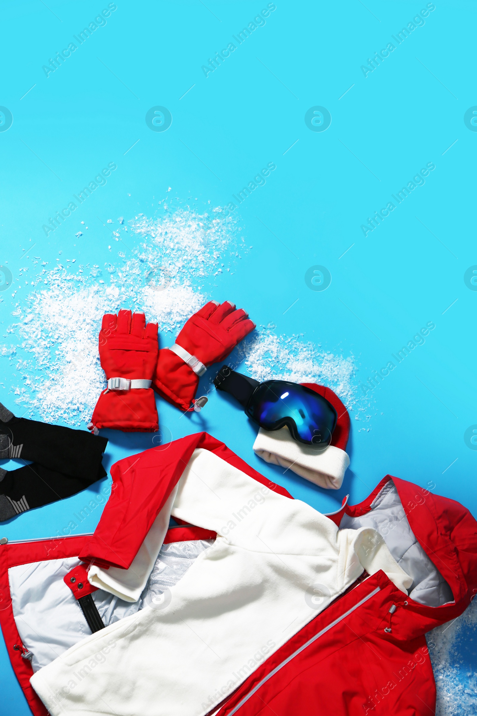 Photo of Stylish winter sport clothes on light blue background, flat lay. Space for text