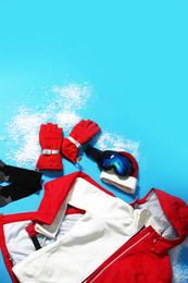 Stylish winter sport clothes on light blue background, flat lay. Space for text