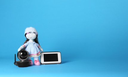 Photo of Modern CCTV security camera, doll and monitor on color background. Space for text