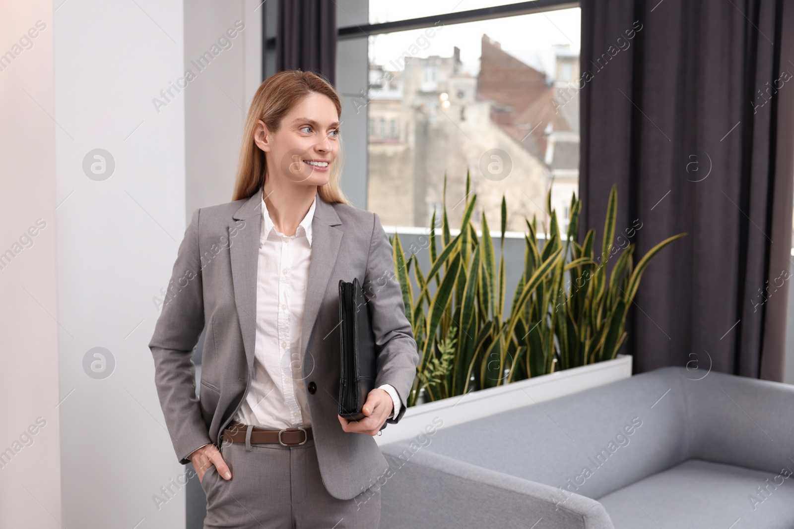 Photo of Happy real estate agent with leather portfolio indoors