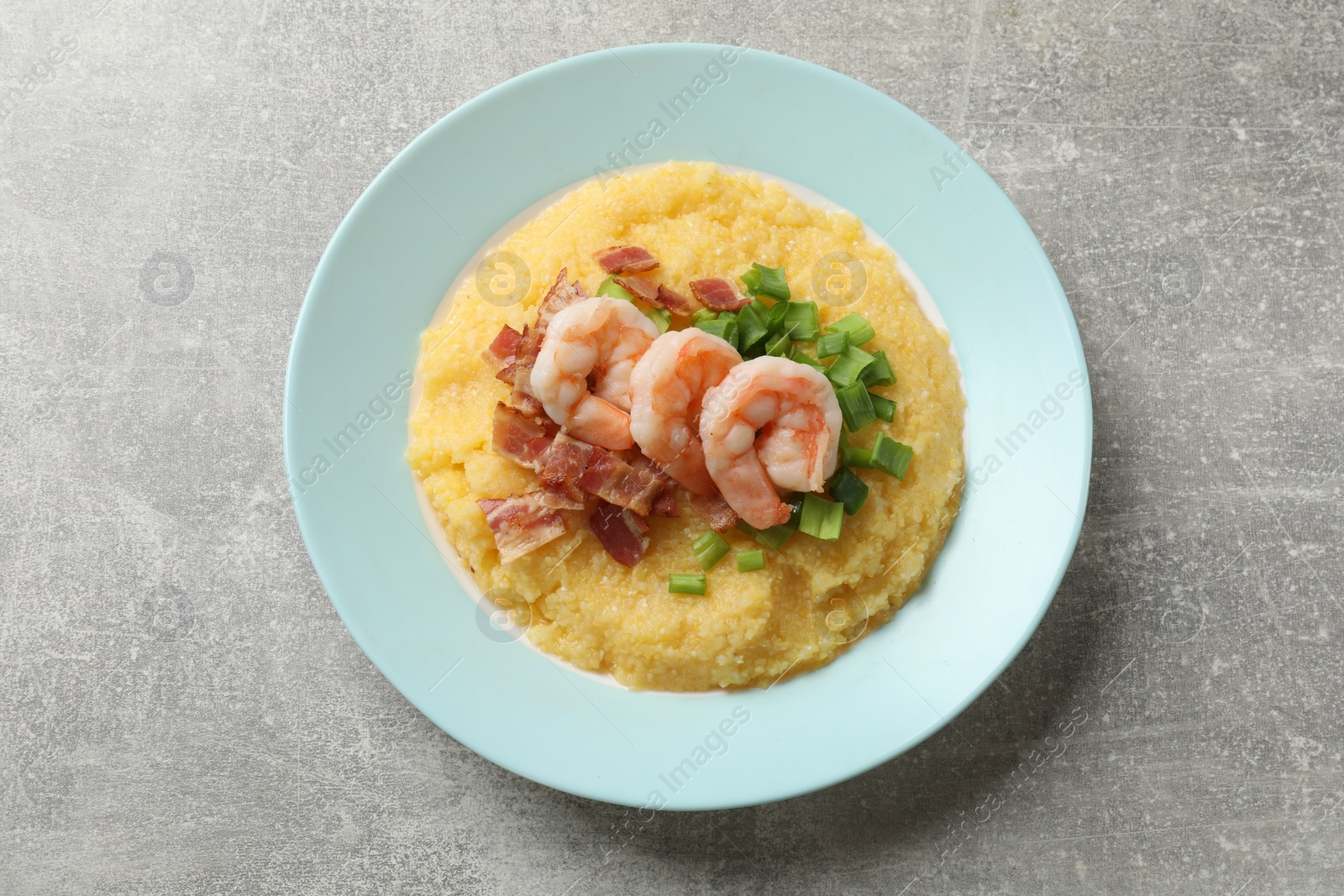 Photo of Plate with fresh tasty shrimps, bacon, grits and green onion on grey table, top view