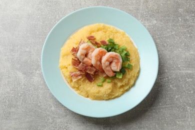 Photo of Plate with fresh tasty shrimps, bacon, grits and green onion on grey table, top view