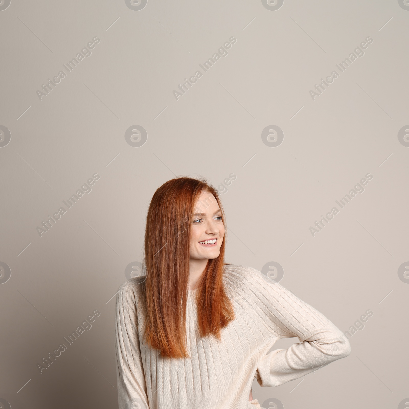 Photo of Candid portrait of happy young woman with charming smile and gorgeous red hair on beige background