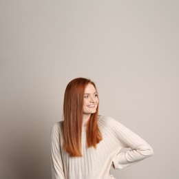 Photo of Candid portrait of happy young woman with charming smile and gorgeous red hair on beige background