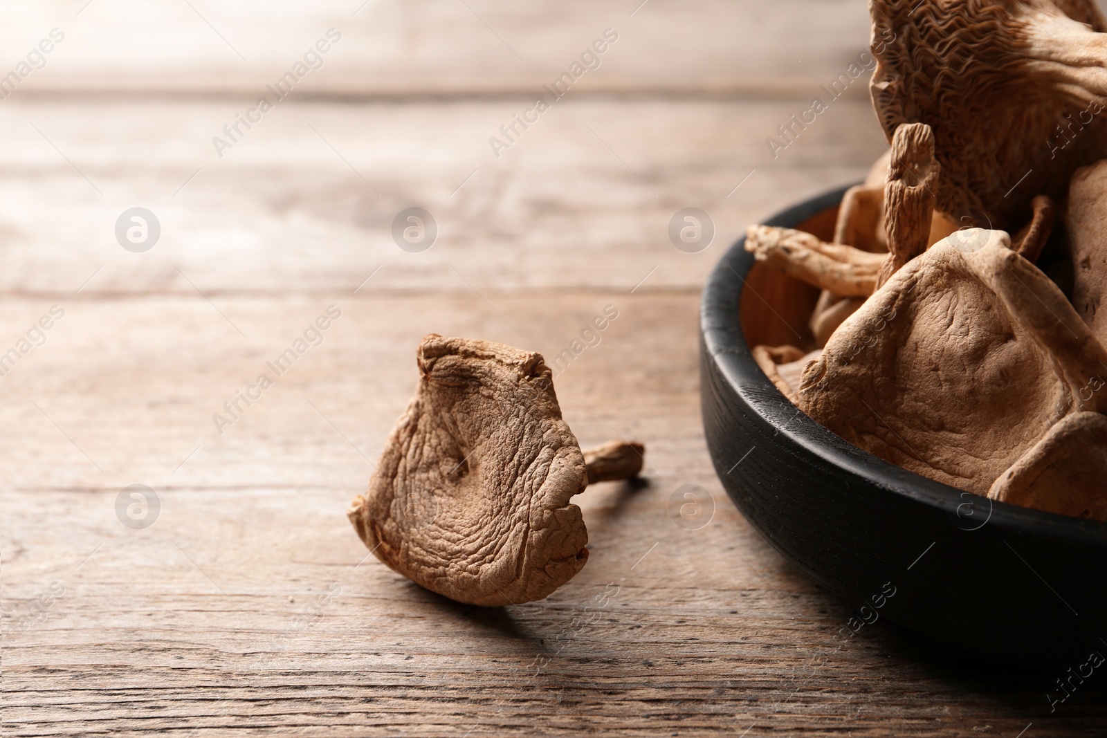 Photo of Composition of dried mushrooms and plate on wooden background