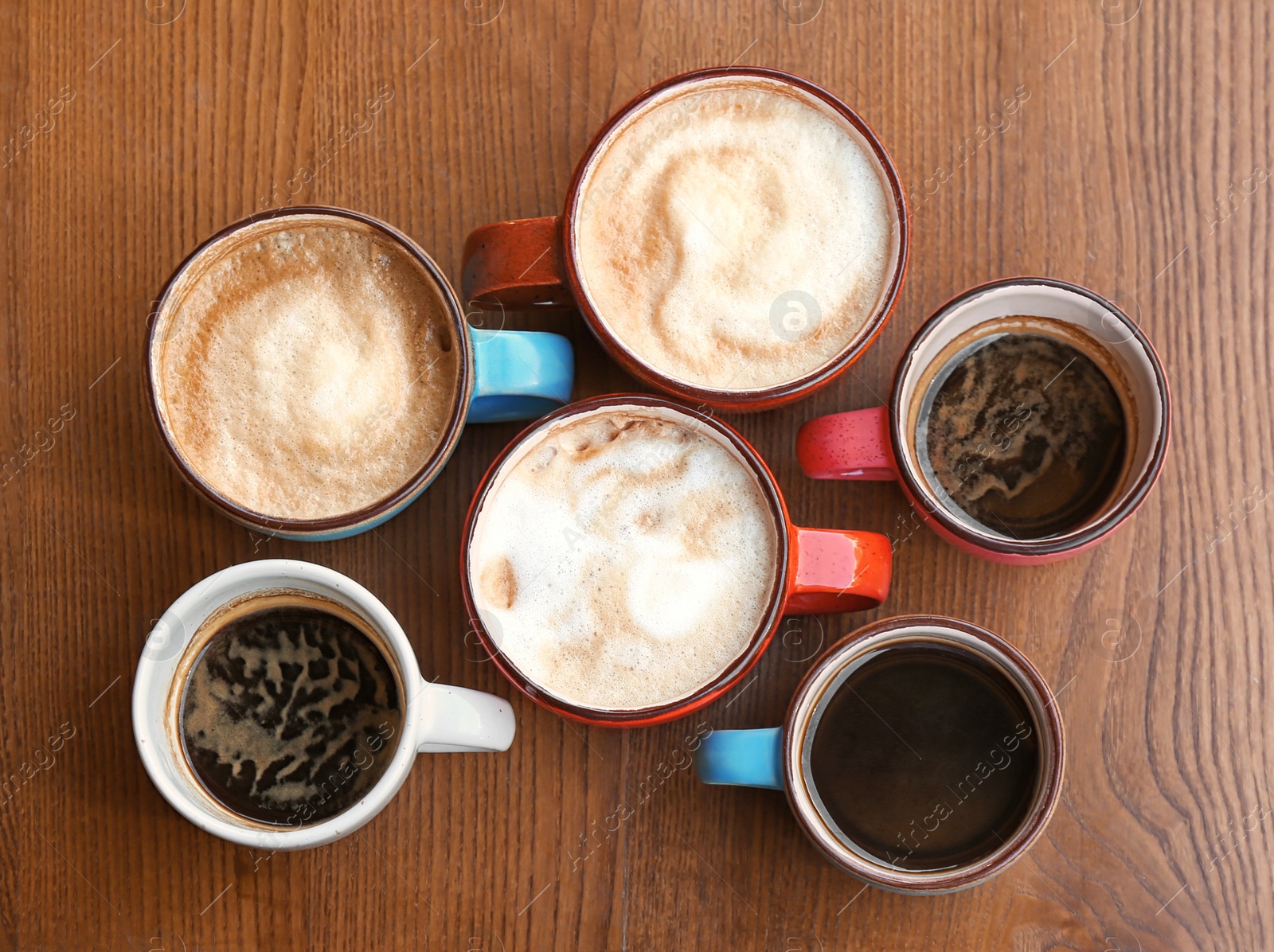 Photo of Cups of fresh aromatic coffee on wooden table, top view