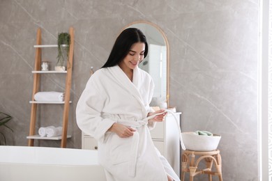 Photo of Beautiful young woman sitting on edge of tub in bathroom