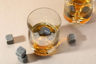 Photo of Whiskey stones and drink in glasses on light table, closeup