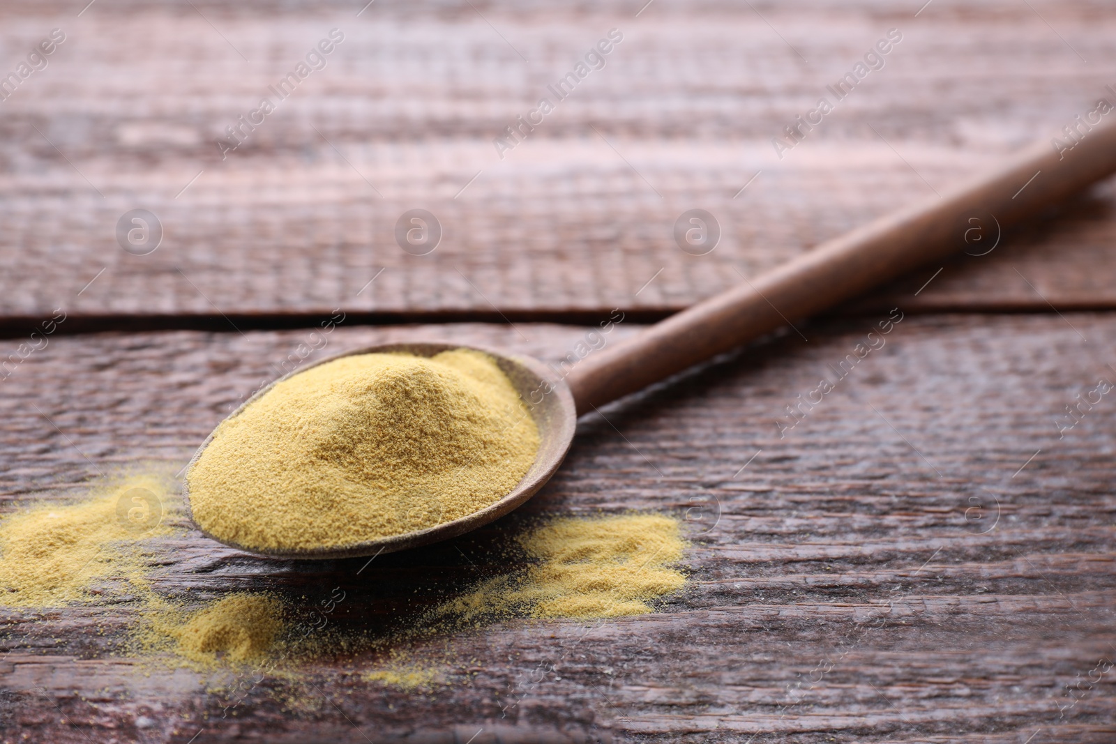 Photo of Brewer's yeast powder in spoon on wooden table, space for text