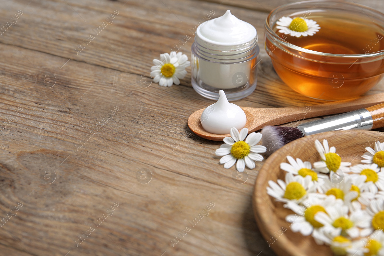 Photo of Composition with chamomile flowers and cosmetic products on wooden table. Space for text