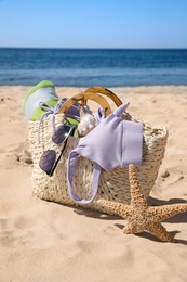 Bag with beach accessories on sand near sea