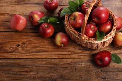 Photo of Fresh ripe red apples and leaves on wooden table. Space for text