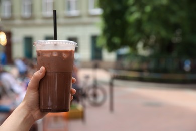 Photo of Woman holding takeaway plastic cup with cold coffee drink outdoors, closeup. Space for text