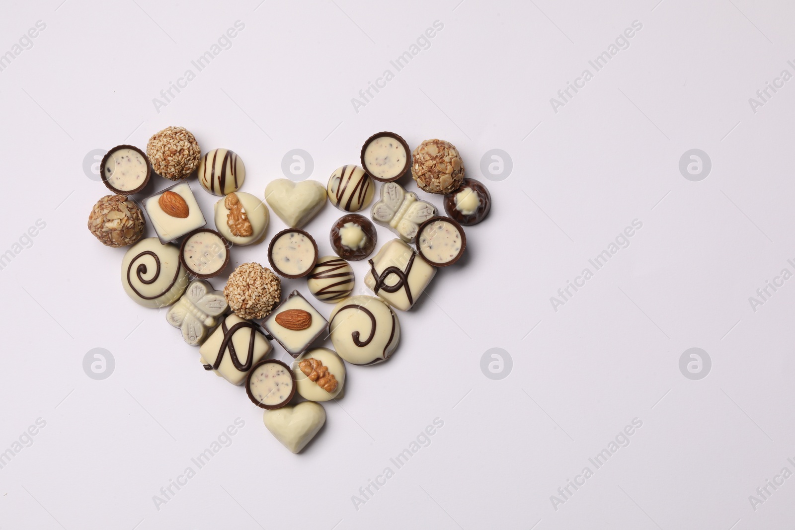 Photo of Heart made with delicious chocolate candies on white background, top view