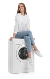 Beautiful young woman on washing machine against white background