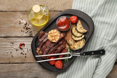 Photo of Delicious grilled beef steak with vegetables and spices on wooden table, flat lay