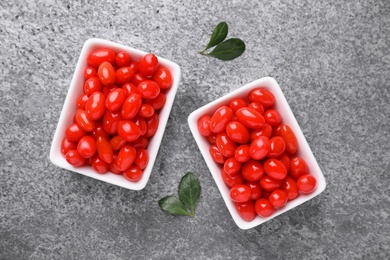 Photo of Bowls with fresh goji berries on grey background, flat lay