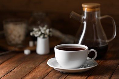 Photo of Cup with delicious tea on wooden table, space for text
