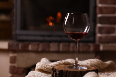 Glass of wine near fireplace indoors. Space for text