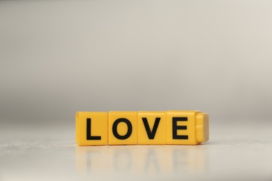 Photo of Word Love made of yellow cubes with letters on light table