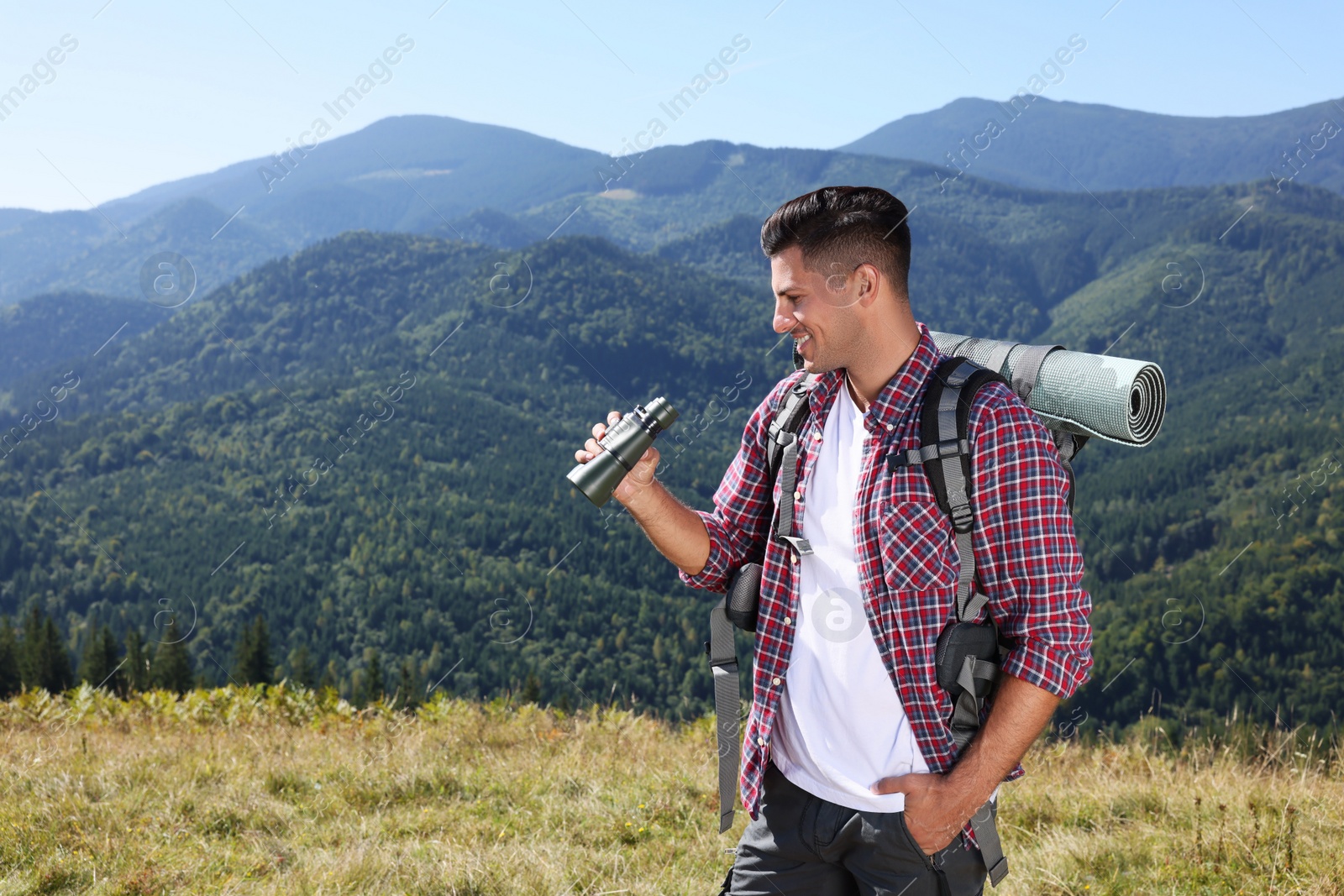 Photo of Tourist with hiking equipment and binoculars in mountains