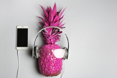 Photo of Pineapple with headphones, glasses and smartphone on grey background, top view with space for text