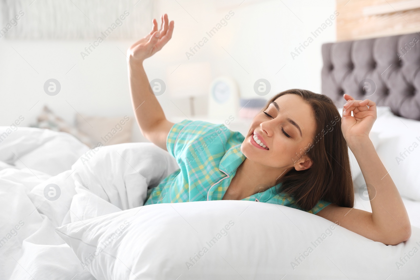 Photo of Portrait of beautiful young woman awakening in large bed