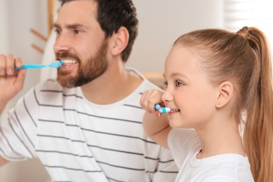 Father and his daughter brushing teeth together indoors