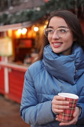 Woman with cup of mulled wine at winter fair