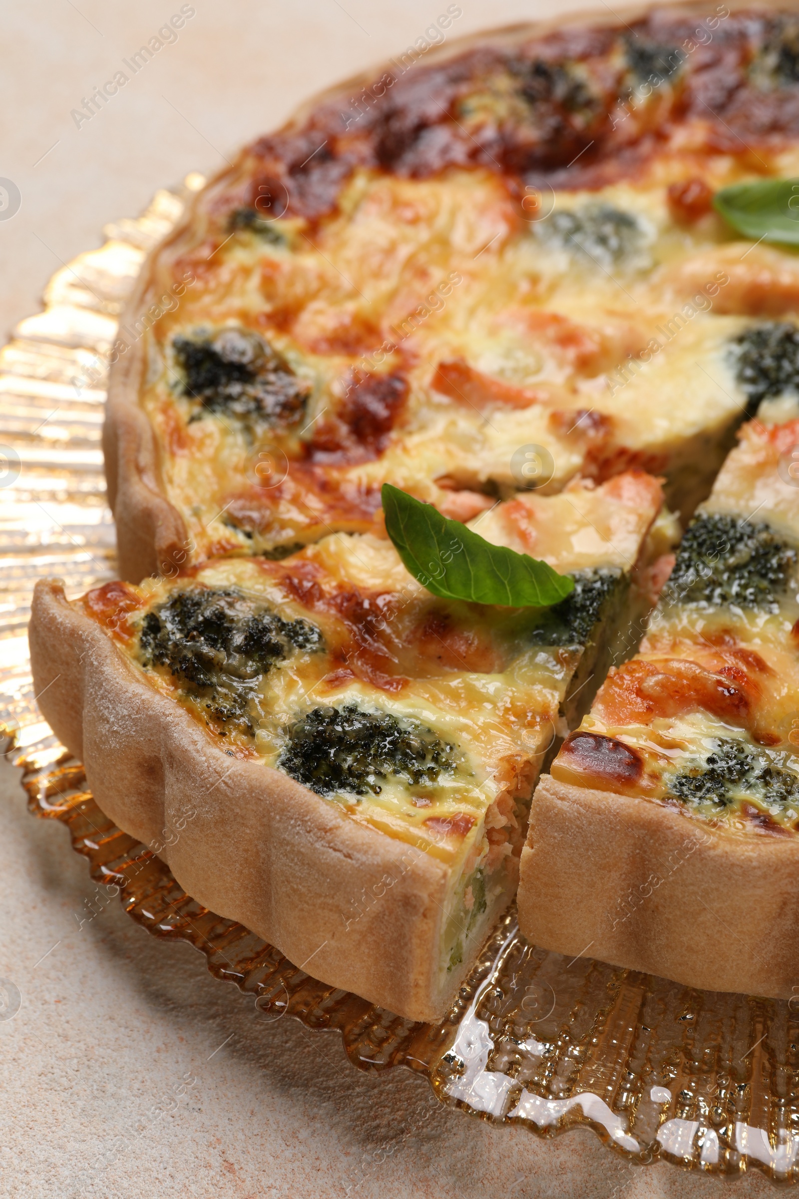 Photo of Delicious homemade quiche with salmon and broccoli on beige table, closeup