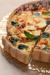 Photo of Delicious homemade quiche with salmon and broccoli on beige table, closeup
