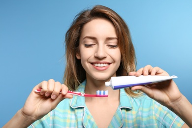 Portrait of young woman with toothbrush and paste on color background