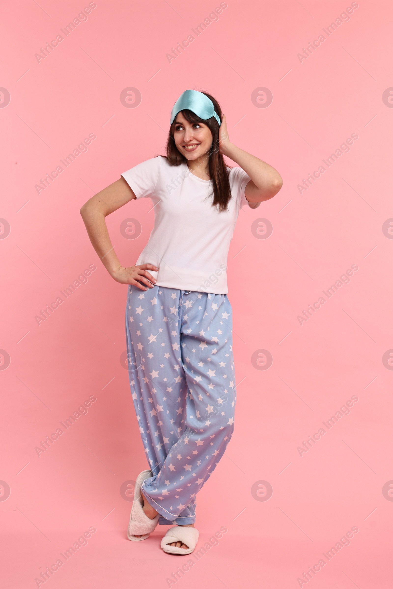 Photo of Happy woman in pyjama and sleep mask on pink background