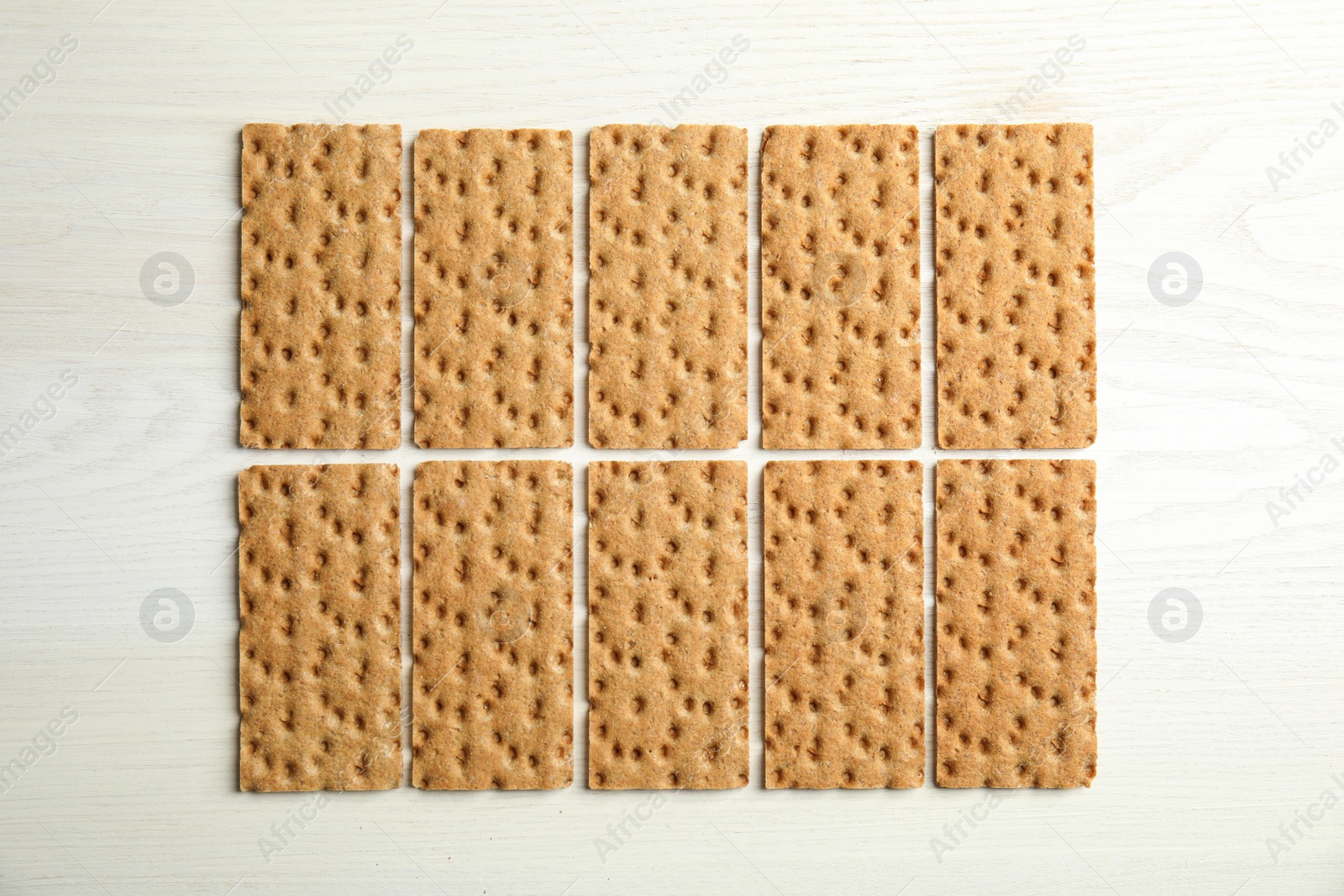 Photo of Fresh rye crispbreads on white wooden table, flat lay