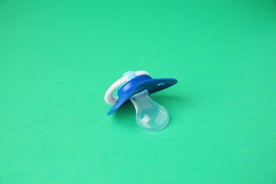 Photo of One blue baby pacifier on green background