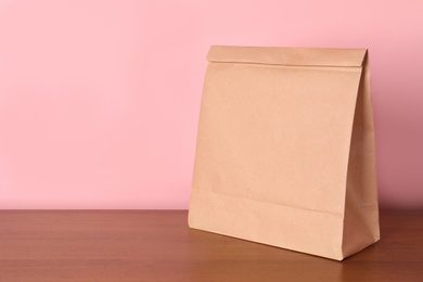 Photo of Paper bag on table against color background. Mockup for design