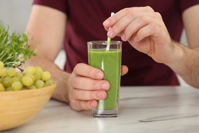 Man drinking delicious fresh smoothie at white marble table indoors, closeup