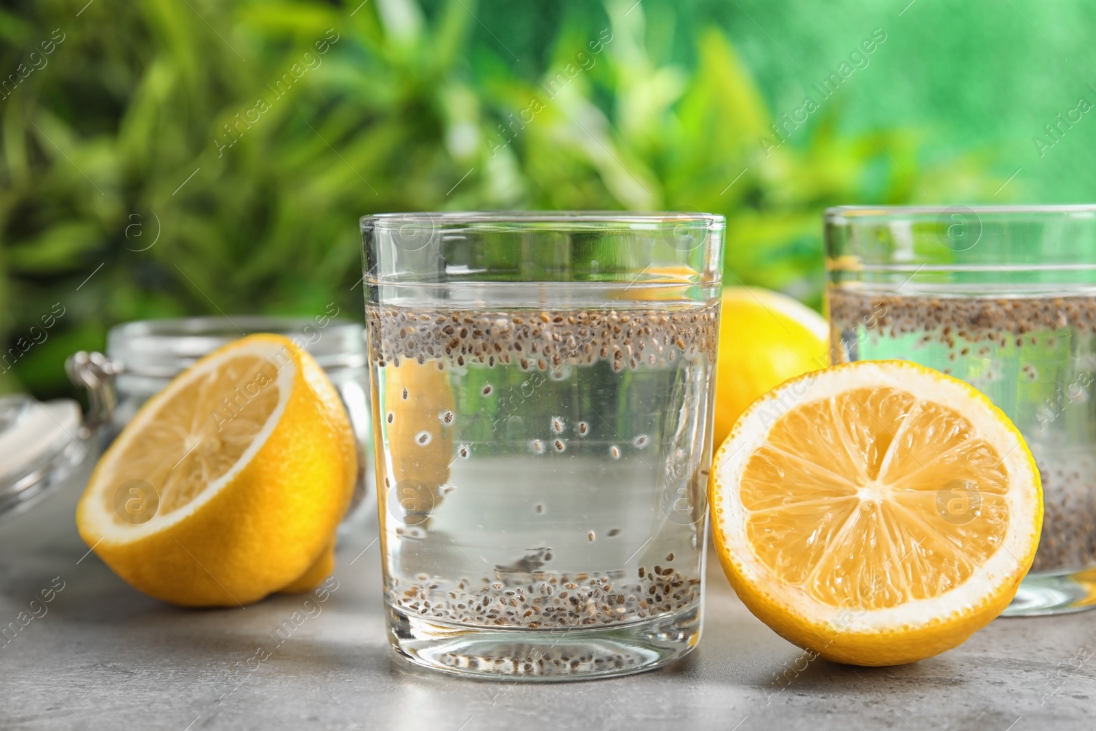 Photo of Glasses of water with chia seeds and lemon on table