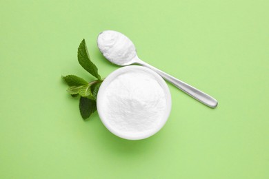 Photo of Sweet powdered fructose and mint leaves on light green background, flat lay